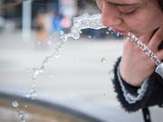   A young woman refreshes herself in a fountain. Due to the persistent drought, the first public wells are closed. Nevertheless, the water supply in Switzerland is not threatened. (Image: KEYSTONE / MELANIE DUCHENE) 