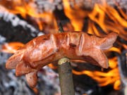 Ein Cervelat brutzelt über dem Feuer. Doch beim Grillieren ist Vorsicht geboten. Wegen der Trockenheit herrscht Waldbrandgefahr. (Bild: Keystone/MARTIN RUETSCHI)