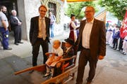 Der Urner Regierungsrat Urs Janett (links) und der Nidwaldner Regierungsrat Alfred Bossard eröffnen in Seelisberg den neuen Wanderweg, indem sie symbolisch zwei Trachtenkinder auf einer Sänfte trugen. (Bild: PD).