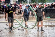 Helfer sind mit Saugschläuchen auf dem Festivalgelände unterwegs.
