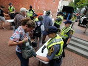 Die Polizei in Charlottesville kontrolliert Taschen. Zum Jahrestag der tödlichen Ausschreitungen an diesem Sonntag haben die Stadt Charlottesville und der Bundesstaat Virginia aus Sorge vor neuen Zwischenfällen den Notstand ausgerufen. (Bild: KEYSTONE/AP/STEVE HELBER)