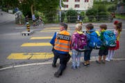 Stadtpolizist Edi Neuschwander begutachtet mit St.Galler Erstklässlern den Strassenverkehr vor einem Zebrastreifen. (Bild: Raphael Rohner)