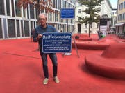 Der St.Galler Historiker überklebte am Montag die Namenstafel des Raiffeisenplatzes mit seiner eigenen Version. (Bild: Christoph Renn)