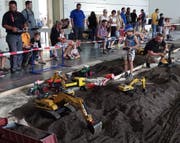 In enger Zusammenarbeit verschiedenster Fahrzeuge wird Erde beladen und andernorts in der Halle verbaut.