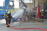 Angehörige der Feuerwehr Weinfelden wässern den Müllberg, der zuvor gebrannt hatte. Mit der Wärmebildkamera wird der Haufen auf Brandnester untersucht. (Bild: Mario Testa)