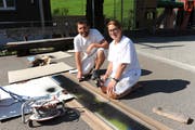 Maler Andreas Gamma und die Maler-Lernende Melinda Inderbitzin bringen mit Farbe und Schablonen den Meridian auf den Schulhausplatz. (Bild: PD, Isenthal, 21. August 2018)