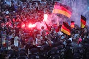 Demonstranten der rechten Szene zünden Pyrotechnik und schwenken Deutschlandfahnen. (Bild: KEYSTONE/DPA/Jan Woitas)