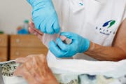 Eine Pflegerin macht einer Patientin einen Verband (Bild: Stefan Kaiser)