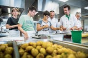 Unter Anweisung der Köche Gerhard Kiniger, Roger Stressle und Jürg Langer helfen die Bewohner in der Küche. (Bild: Andrea Stalder)