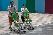 Das Reich der Mitte braucht dringend Nachwuchs: Eltern fahren ihre Zwillinge durch die Strassen Pekings spazieren. (Bild: Roman Pilipey/EPA; 10. August 2018)