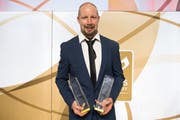 Der Uzwiler Mathias Seger mit dem Hockey Award für den «Most Popular Player» in der rechten und dem Special Award in der linken Hand. (Bild: Keystone/Daniel Teuscher)