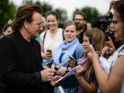 U2-Sänger Bono spricht mit Fans, nachdem er vergangene Woche mit der deutschen Kanzlerin Angela Merkel über Entwicklungshilfe in Afrika gesprochen hat. Bei einem Konzert in Berlin hat am Samstag seine Stimme versagt und die Veranstaltung musste abgebrochen werden. (Bild: KEYSTONE/EPA/CLEMENS BILAN)