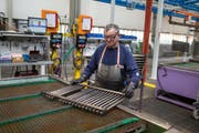 Ein Mitarbeiter der Arbonia-Produktion prüft einen Heizkörper auf Lecks. Bild: Gaëtan Bally/Keystone (Arbon)