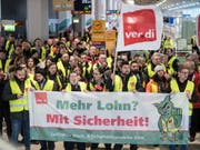 Mitglieder der Gewerkschaft Verdi stehen am Flughafen Köln mit Fahnen und einem Transparent. (Bild: Keystone/DPA/FEDERICO GAMBARINI)