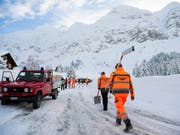 Männer mit Schaufeln passieren am Freitag eine Strassensperre auf der Passhöhe, nach einem Abgang einer 300 Meter breiten Lawine auf der Schwägalp AR. Nach derzeitigen Erkenntnissen wurden drei Personen leicht verletzt. (Bild: KEYSTONE/GIAN EHRENZELLER)