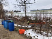 Feuerwehrangehörige errichten eine Ölsperre in der Bünz. (Bild: Kantonspolizei Aargau)