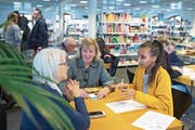 Die 16-jährige Lulya Araya (gelber Pulli) weiht Inge Thomi (links) und Margrith Lanninger in die Geheimnisse ihres Smartphones ein. (Bild: Maria Schmid (Zug, 12. Januar 2019))