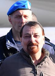Ein Polizist eskortiert Cesare Battisti bei seiner Ankunft im Flughafen in Rom. Bild: Ettore Ferrari/EPA (Rom, 14. Januar 2019)