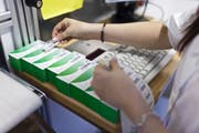 In einer Apotheke setzt ein Mitarbeiter Strichcodes auf Medikamentenpackungen. (Bild: Gaetan Bally/Key)