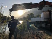 Walliser Kantonspolizisten bei der Bergung des Autowracks aus der Rhone. Nun steht fest, dass im Auto ein Mann und ein Mädchen gesessen hatten, die seit einem Unwetter vermisst werden. (Bild: KEYSTONE/KANTONSPOLIZEI WALLIS)