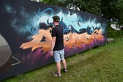 Ein Sprayer fertigt ein Kunstwerk an der Holzwand auf der Kreuzbleiche an. (Bilder: PD)