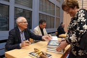 Peter Bolli und Ernest Menolfi signieren an der Vernissage in der Mehrzweckhalle Hauptwil ihr Buch. (Bild: Yvonne Aldrovandi-Schläpfer)