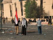 Frustration über Korruption und Stillstand: Irakische Sicherheitskräfte riegeln die Grüne Zone in Bagdad ab, während im Vordergrung Zivilisten demonstrieren. (Bild: KEYSTONE/AP/HADI MIZBAN)