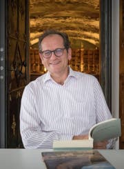 Der St.Galler Stiftsbibliothekar Cornel Dora in der Handschriftenkammer; im Hintergrund der berühmte Barocksaal der Stiftsbibliothek. (Bild: Lisa Jenny)