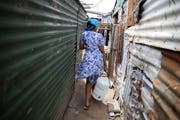 Eine Frau trägt in einem Township in der Nähe von Kapstadt Wasser zu ihrer Unterkunft. Die herrschende Armut breiter Bevölkerungsschichten bleibt für Südafrika auch 25 Jahre nach dem Ende der Apartheid eines der grossen Probleme. (Bild: Nic Bothma/Keystone - 6. November 2019)