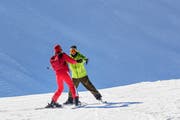 Ein Skilehrer hilft einer Skischülerin, sich richtig auf den Brettern zu bewegen. (Bild: Getty)