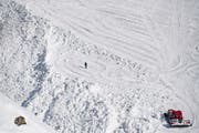 Am Tag nach dem Unglück: Ein Pistenbully neben dem Lawinenkegel. (Bild: Jean-Christophe Bott / Keystone)