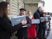 Mitglieder des Komitees reichen am Montag bei der Bundeskanzlei die Unterschriften für die Petition «Hürden abbauen - Behandlung psychischer Krankheiten sicherstellen» ein. (Bild: Keystone/PETER KLAUNZER)
