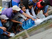 Prekäre Wasserversorgung in Venezuela wegen des Stromausfall: Menschen in der Hauptstadt Caracas holen sich Wasser bei einer leckgeschlagenen Leitung. (Bild: KEYSTONE/AP/FERNANDO LLANO)