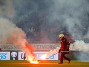 Das Löschen nützt nichts, der Schiedsrichter bricht das Spiel ab: Zuschauer aus dem GC-Sektor warfen Feuerwerkskörper auf den Rasen des Tourbillon (Bild: KEYSTONE/SALVATORE DI NOLFI)
