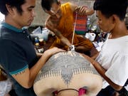 Auf dem traditionellen Tattoo-Fest im Wat-Bang-Phra-Tempel sticht ein buddhistischer Mönch einem Gläubigen mit einem angespitzten Stahlstab ein neues Tattoo. (Bild: KEYSTONE/EPA/NARONG SANGNAK)