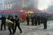 Polizisten sichern ein in Flammen stehendes Restaurant. Bild: Yoan Valat/EPA (Paris, 16. März 2019)