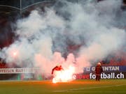 Feuerwehrleute entfernen brennende Petarden vom Spielfeld am Samstag in Sitten. (Bild: KEYSTONE/SALVATORE DI NOLFI)