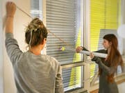 Zwei Schülerinnen der Zürcher Schule für Gestaltung bereiten das Bekleben der Rollläden vor.