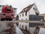 Ein Feuerwehrwagen steht neben einem Haus mit Brandspuren. Bei dem Brand in dem Nürnberger Wohnhaus sind vier Kinder und eine Frau ums Leben gekommen. (Bild: Keystone/DPA/LINO MIRGELER)