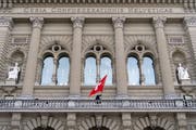 Eine Person installiert die Schweizer Flagge auf dem Balkon vor dem Ständerat beim Bundeshaus. (Bild: Anthony Anex / Keystone, Bern, 12. März 2019)