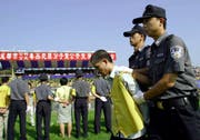 Chinesische Polizisten halten im Stadion in Shuangliu einen verurteilten Drogenhändler fest. (Bild: AFP)