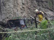 Ein Rettungsarbeiter sucht im Schlamm und unter umgestürzten Bäumen nach möglichen Opfern. (Bild: KEYSTONE/AP/SILVIA IZQUIERDO)