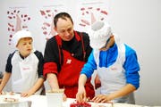 Zwei Kinder lernen von Fleischfachmann Reto Rust (Mitte), wie ein Schwägalpspiessli entsteht. (Bild: Michael Hehli)