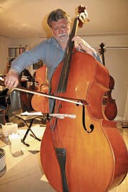 Francisco Obieta greift zu einem der vier Kontrabasse in seiner Stube in Au, um ein Stück zu spielen. (Bild: hb)