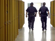 US-Polizisten patrouillieren durch den Gang mit Schliessfächern einer Schule. (Bild: KEYSTONE/AP The Citizens' Voice/KRISTEN MULLEN)