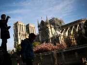 Ein Tourist macht am Mittwoch ein Foto von Notre Dame - Frankreichs Kabinett beriet gleichentags über den Wiederaufbau nach dem Brand der Kathedrale. (Bild: KEYSTONE/AP/FRANCISCO SECO)
