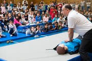 Arzt Rommel Jadaan zeigt an einer Puppe, wie die Herzdruckmassage geht. Die Kinder schauen gespannt zu. (Bild: Eveline Beerkircher, Kriens, 18. April 2019)