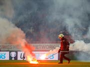 Ein Feuerwehrmann entfernt im Tourbillon einen Pyro-Wurfkörper. (Bild: KEYSTONE/SALVATORE DI NOLFI)