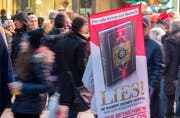 Mit einem Plakat auf dem Rücken versucht ein Teilnehmer der Koran-Verteilaktion «Lies» in Frankfurt die Aufmerksamkeit auf sich zu ziehen. (Bild: KEYSTONE/DPA/Boris Roessler)
