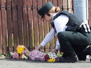 Eine Polizistin legt am Ort Blumen nieder, an dem in Derry eine 29-jährige Journalistin getötet wurde. Die Polizei meldete am Samstag die Festnahme von zwei Verdächtigen. (Bild: KEYSTONE/EPA/JOE BOLAND / NORTH WEST NEWSPIX)